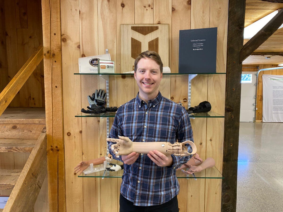 Easton LaChappelle holding a prosthetic arm at Unlimited Tomorrow headquarters in Rhinebeck