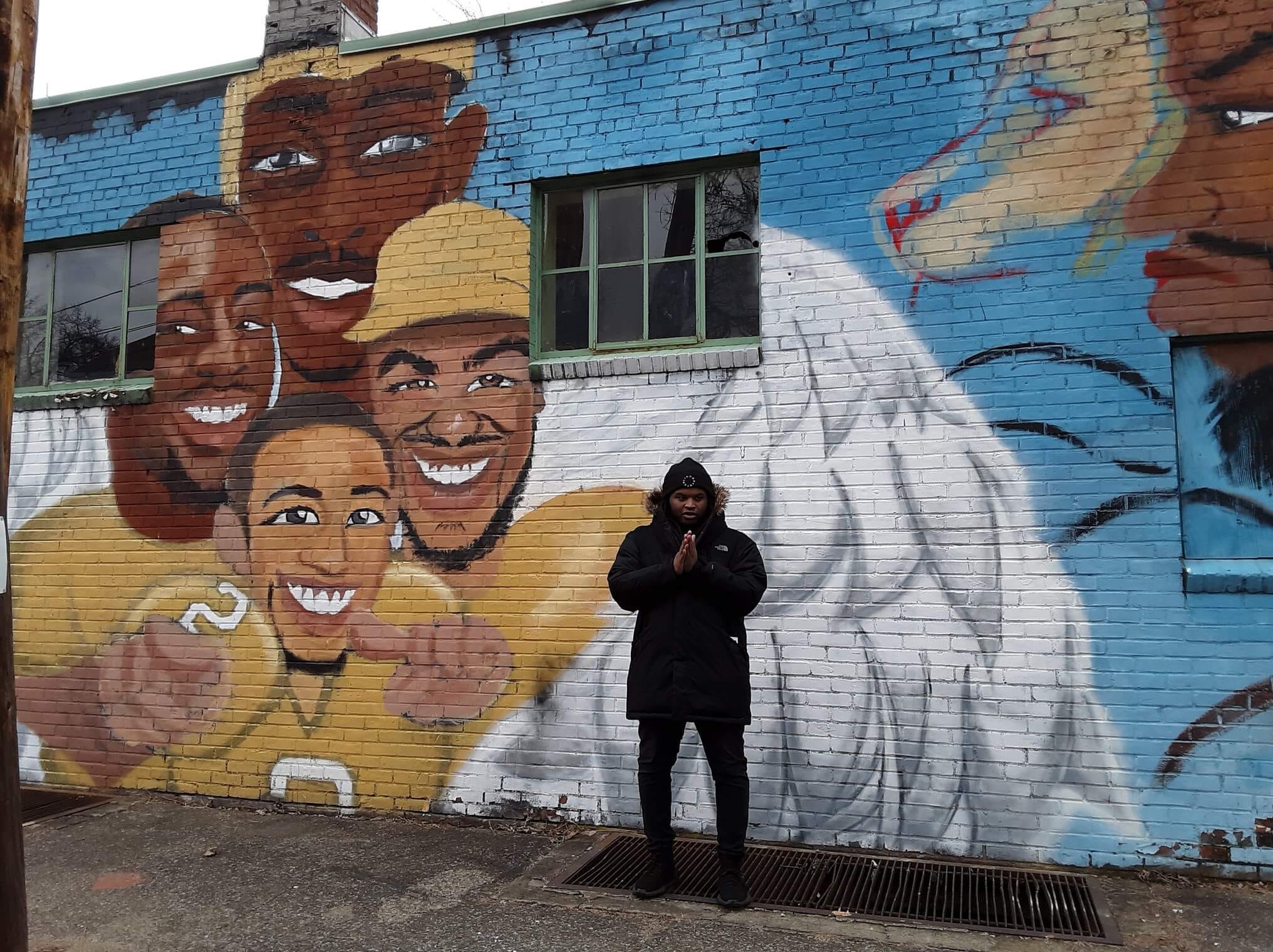 Jalani in front of his first mural, on Franklin Street in Kingston.